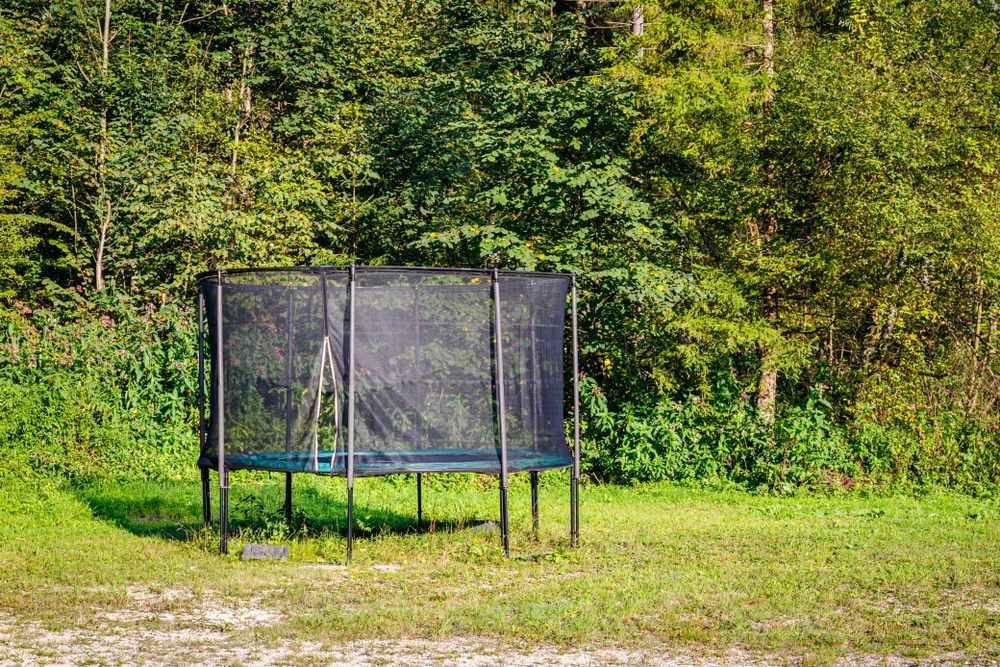 a normal trampoline with safety walls in the corner of a garden