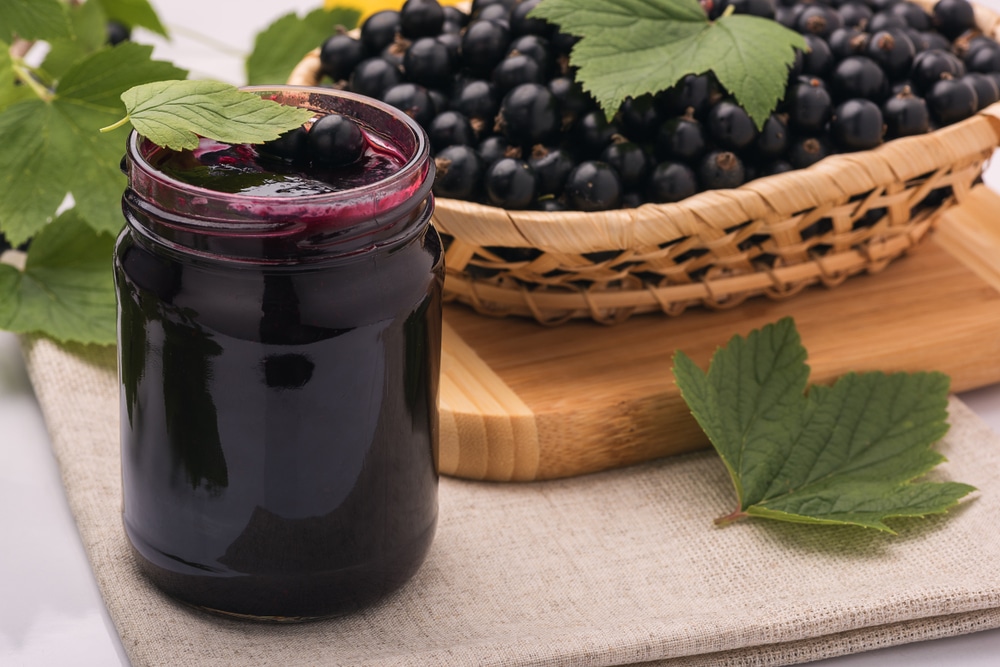 blackcurrant jam in a jar and a basket of blackcurrants