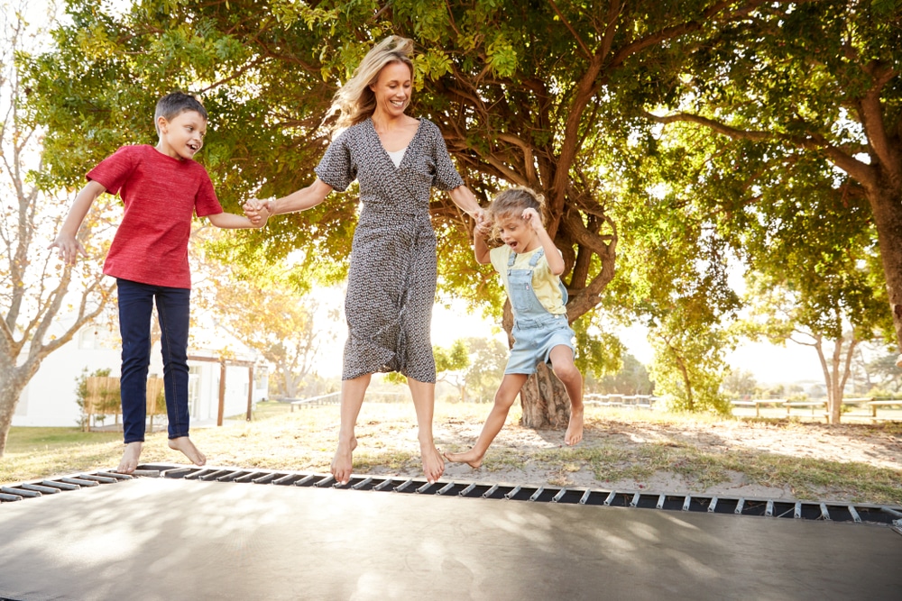 a mother and two children using a sunken trampoline