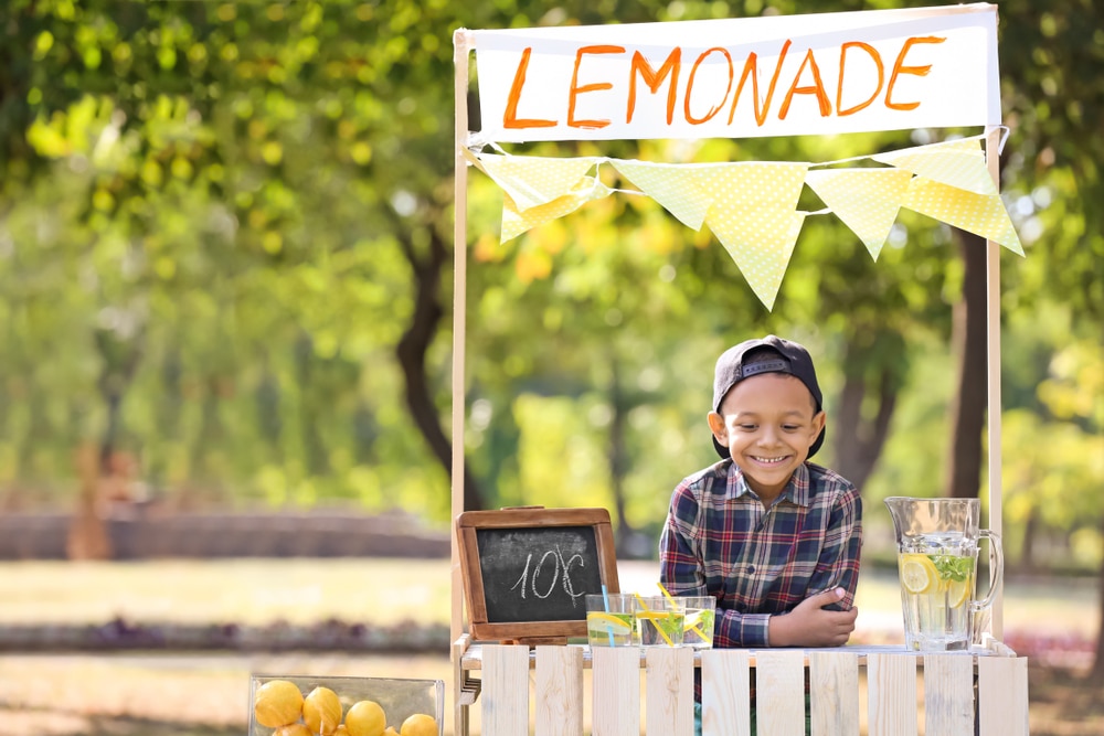 kid selling lemonade on stall in garden