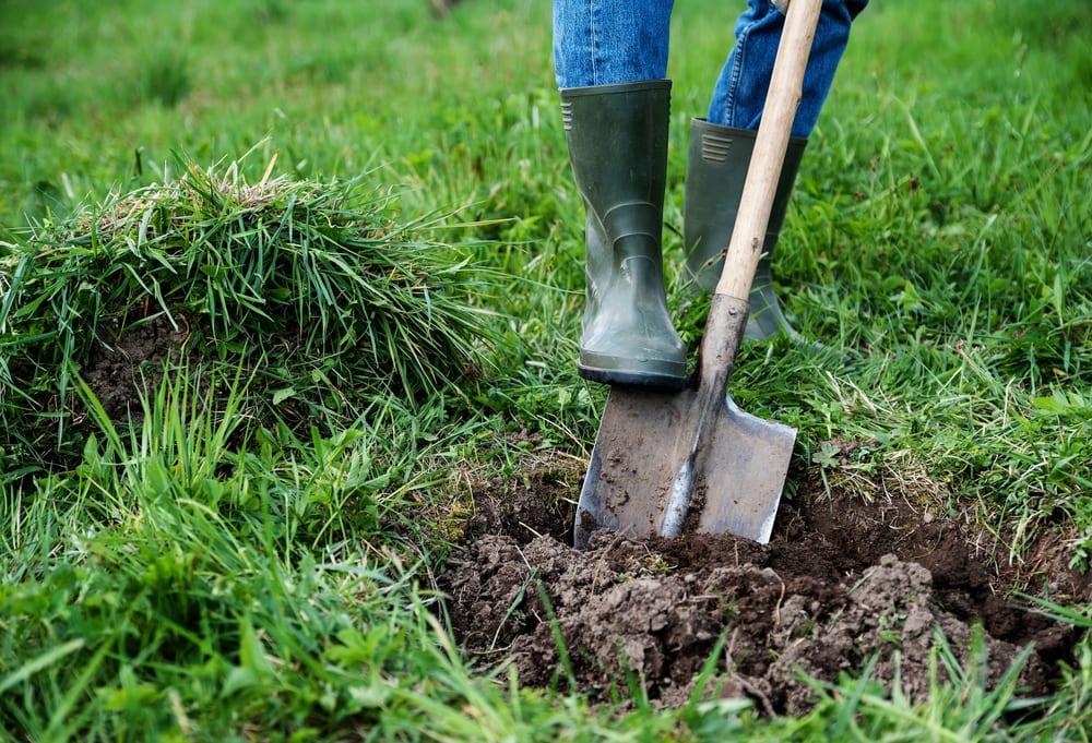 man in green wellies digging turf with a spade