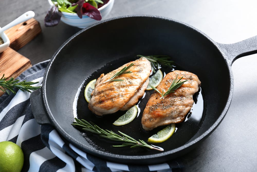 chicken breasts in a frying pan topped with rosemary and lemon